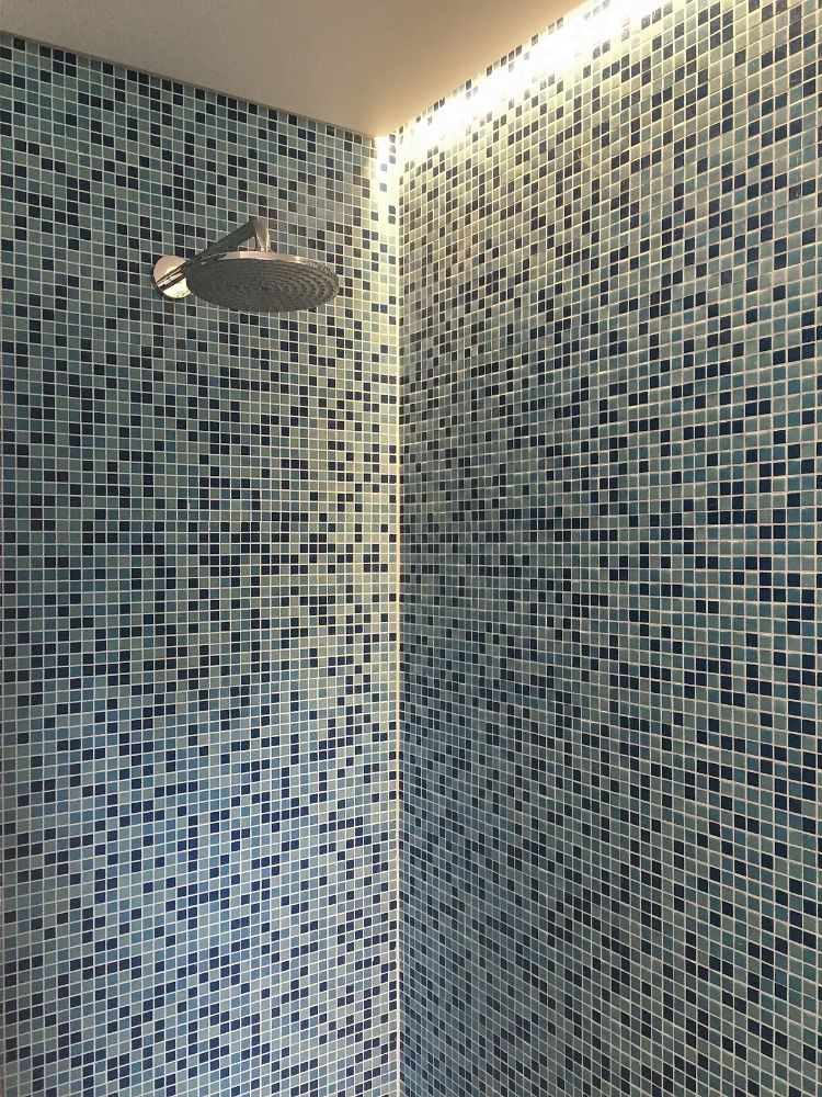 Blauwe mozaïekdouche met wandlamp