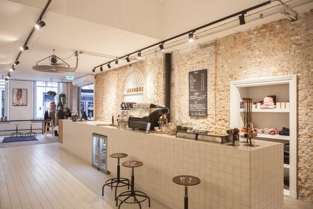Een lichte koffiezaak met een lange balie en bakstenen muur
