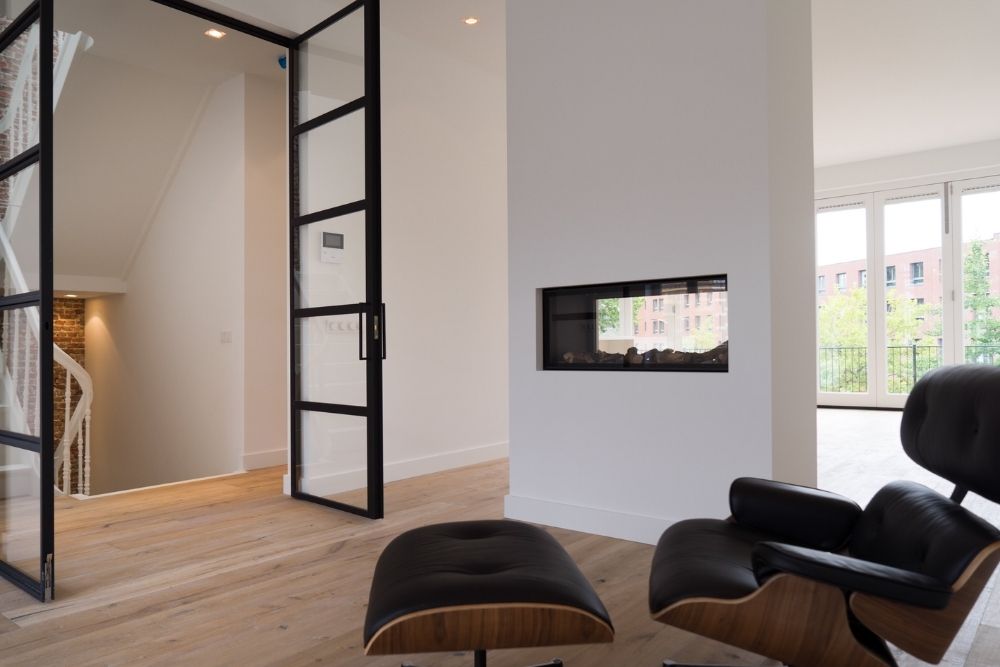 Een lichte woonkamer met haard en een moderne stoel