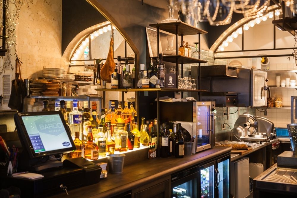 Een sfeervolle bar met warme verlichting flessen drank en glazen op de toonbank