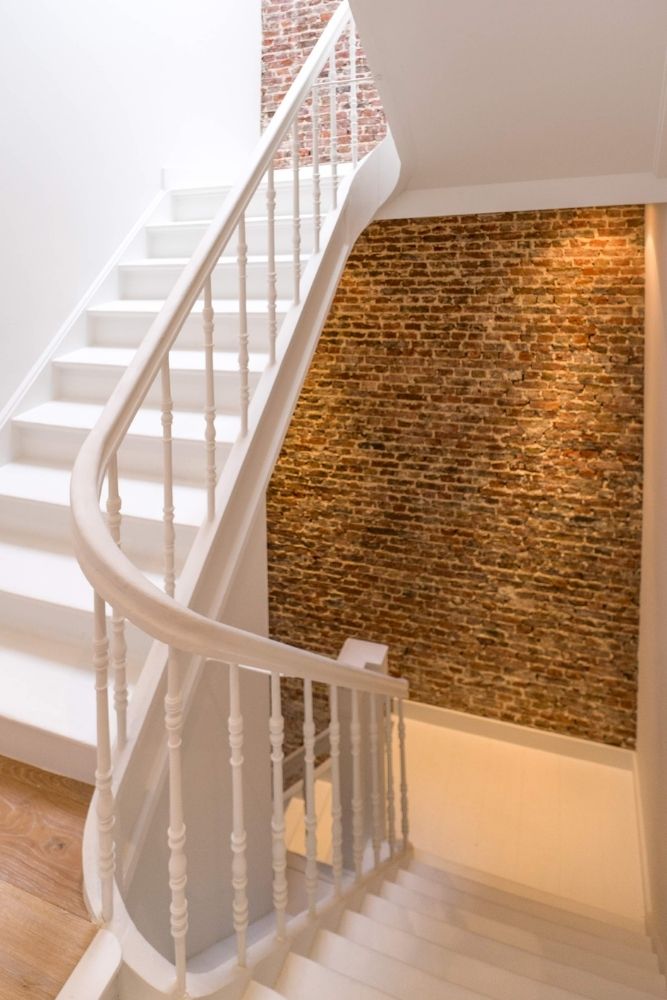 Gebogen trap naast verlichte bakstenen wand