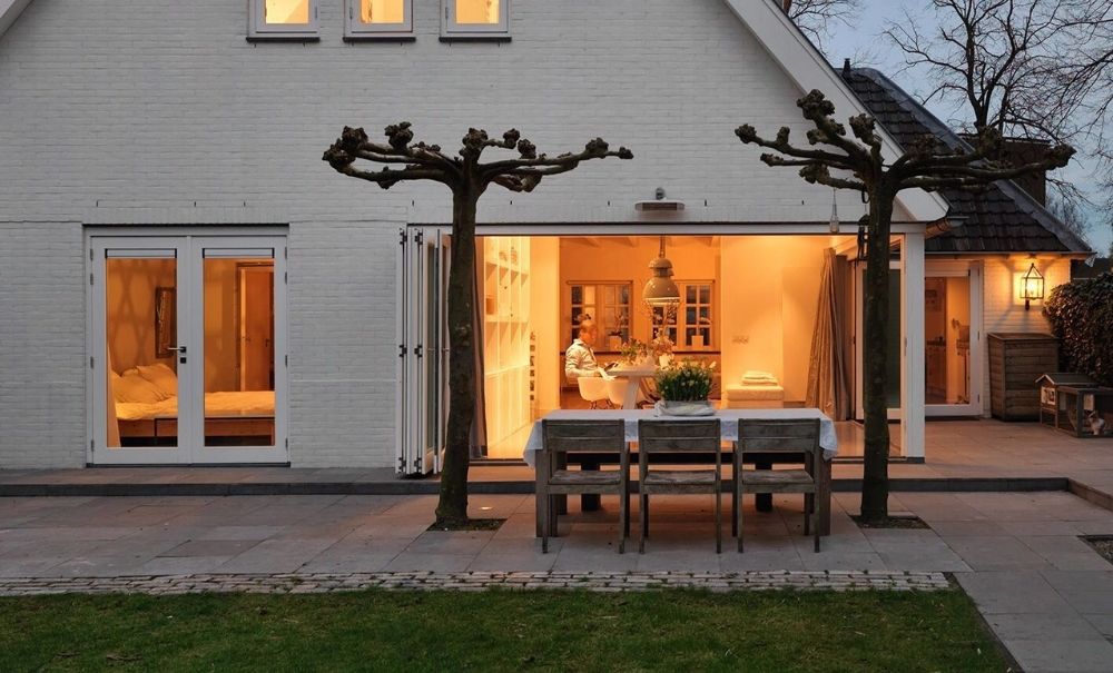 Gezellig huis met open schuifdeuren naar een gedekte buitentafel