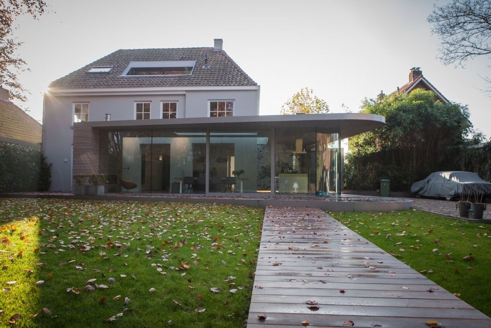 Huis met grote ramen en een houten pad in de tuin