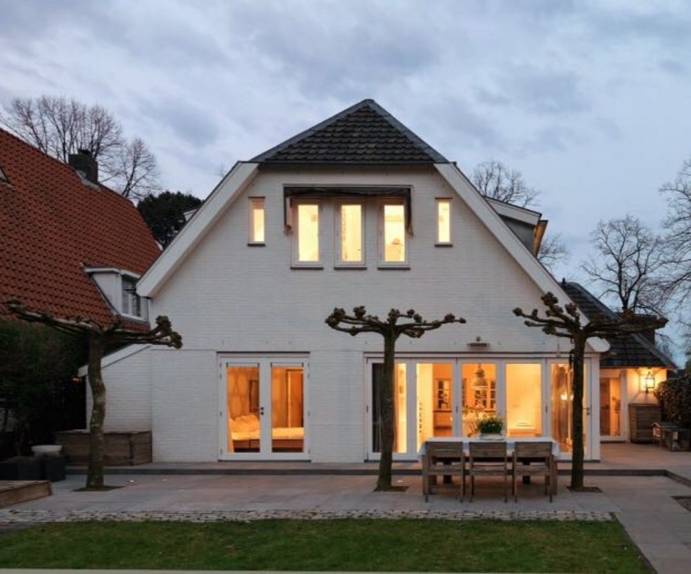 Huis met grote ramen en verlicht terras in de schemering