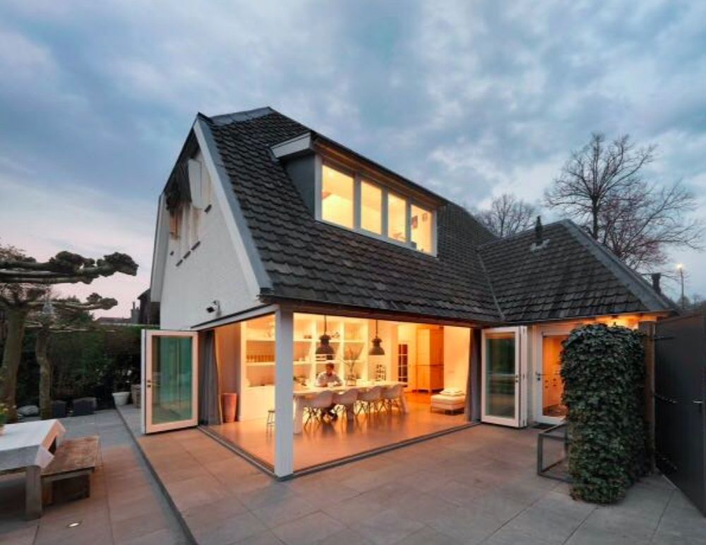 Moderne woning met grote ramen die uitkijken op een verlichte eetruimte