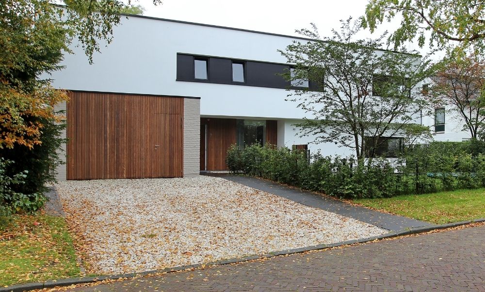 Moderne woning met oprit garage en omringende bomen