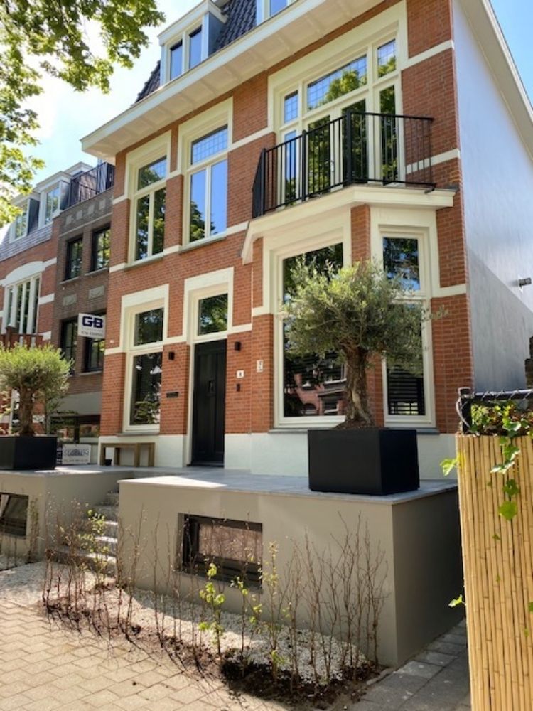 Rijwoning met rood witte gevel en groene voortuin