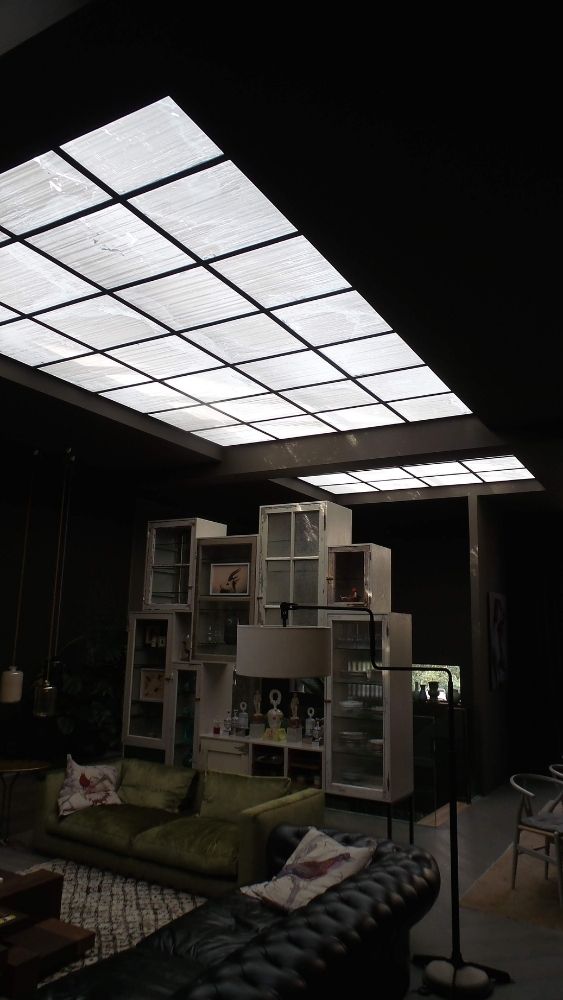Ruime woonkamer met groot lichtplafond en moderne meubels