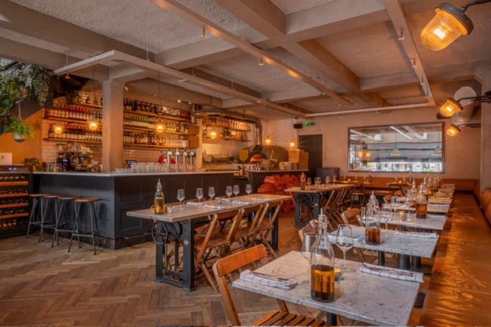 Gezellige eetruimte van Pazzi met houten stoelen en open bar