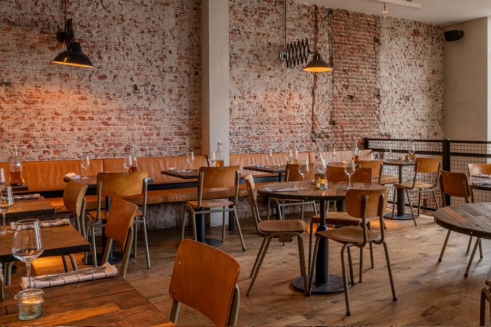 Interieur van restaurant Pazzi met bakstenen muren en houten tafels