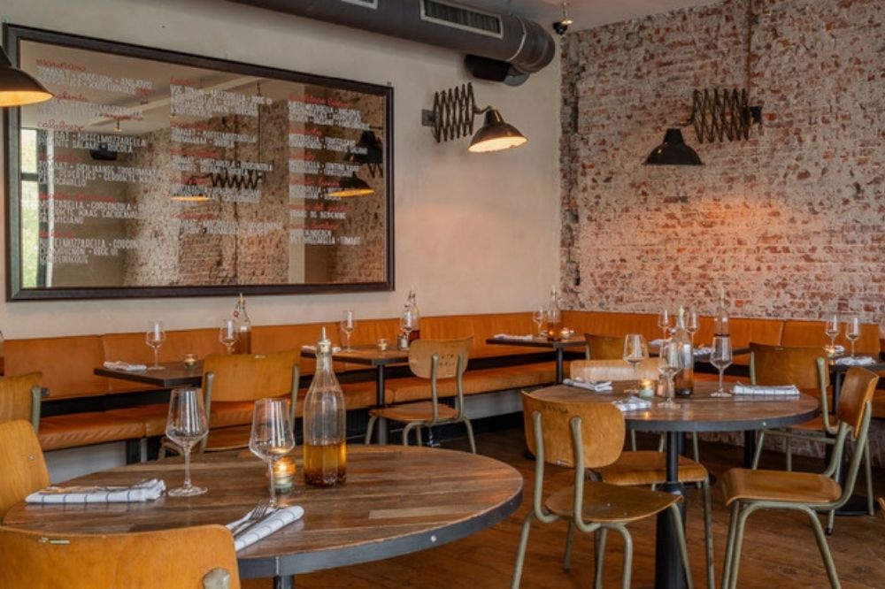 Interieur van restaurant Pazzi met houten tafels en stoelen