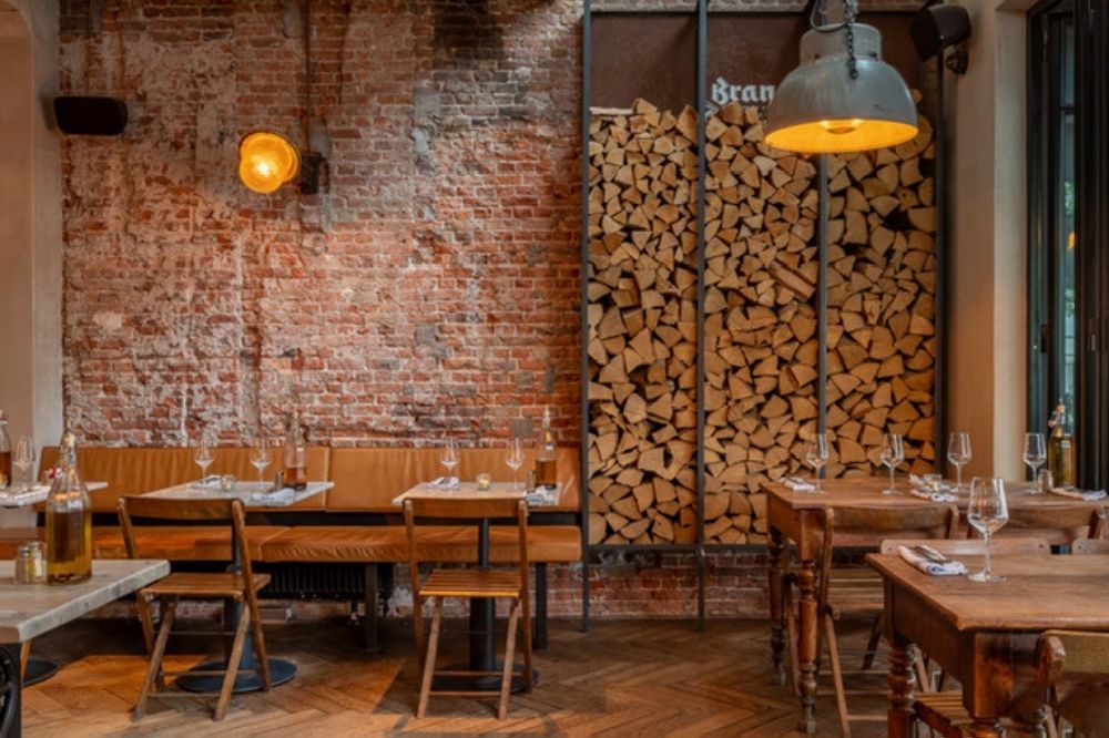 Interieur van restaurant Pazzi met houten tafels en warme baksteenmuren