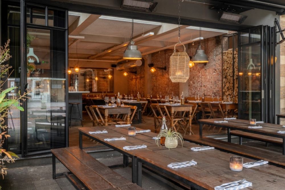 Interieur van restaurant Pazzi met houten tafels en warme sfeer