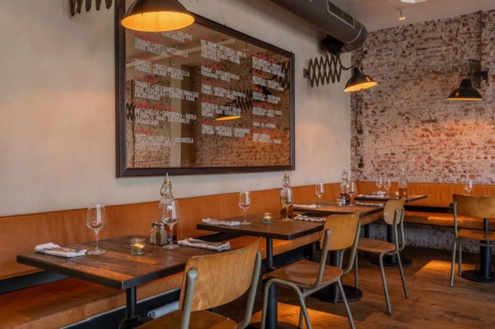 Interieur van restaurant Pazzi met houten tafels en warme verlichting